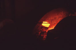 玉鋼を火床の中で赤めて叩く工程が繰り返される。