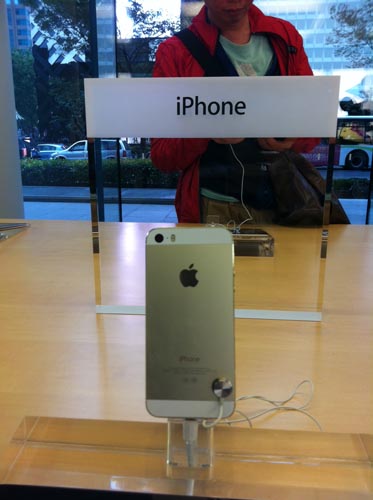 「土豪金」ことゴールドカラーのiPhone 5sと店頭で試す客（Apple Store上海淮海路店）